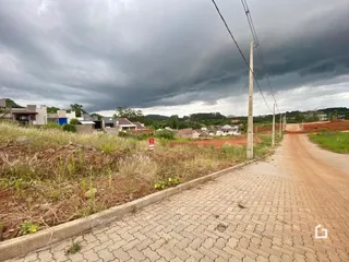 Vista de uma estrada de terra com pavimento de tijolos em uma área rural sob um céu nublado.