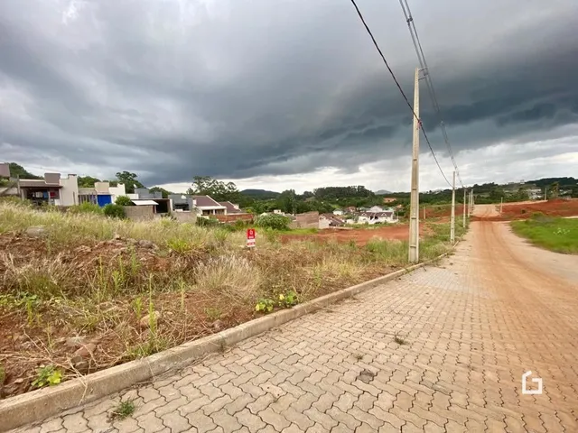 Vista de uma estrada de terra com pavimento de tijolos em uma área rural sob um céu nublado.