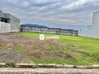 Vista externa de um terreno com grama seca e muros de concreto.
