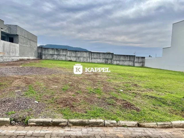 Vista externa de um terreno com grama seca e muros de concreto.