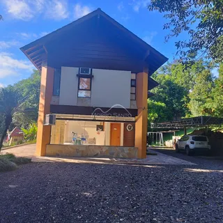 Fachada de uma casa em Lajeado, Brasil, com telhado inclinado e revestimento em tons terrosos.