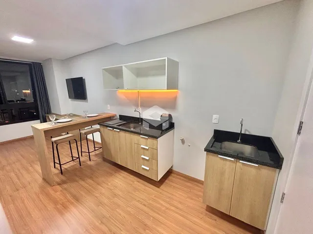 Foto de uma cozinha e sala de jantar com piso de madeira clara.