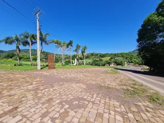 Vista externa de um terreno pavimentado com árvores e uma estrada no Brasil.