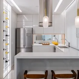 Cozinha moderna com armários brancos e eletrodomésticos de aço inoxidável.