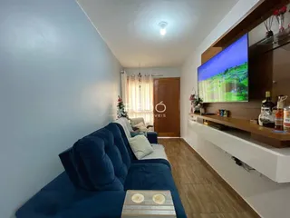 Sala de estar com sofá azul e piso de madeira em um imóvel no Brasil.