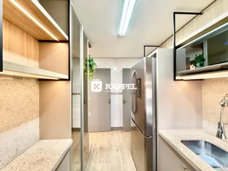 Interior da cozinha com armários de madeira e bancadas claras.