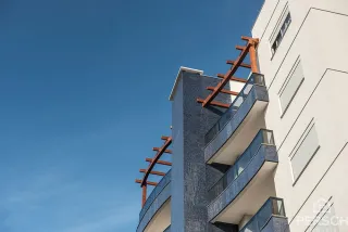 Fachada de um prédio moderno com varandas azuis e detalhes em metal laranja.