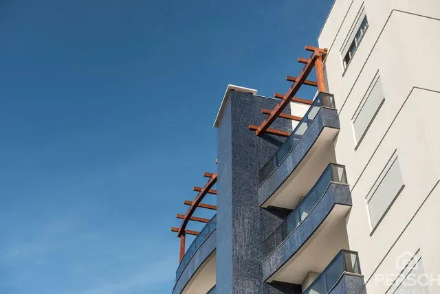 Fachada de um prédio moderno com varandas azuis e detalhes em metal laranja.