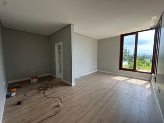 Esta é uma sala ampla com piso de madeira e uma grande janela com vista para a paisagem.