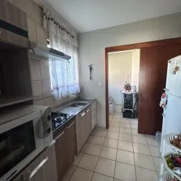 Foto interna de uma cozinha com armários e piso de cerâmica.