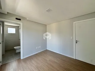 Imagem de um ambiente interno com piso de madeira e porta de acesso a um banheiro.