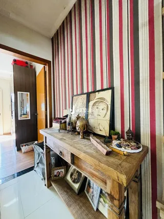 Interior de um corredor com parede listrada e um aparador de madeira rústica.