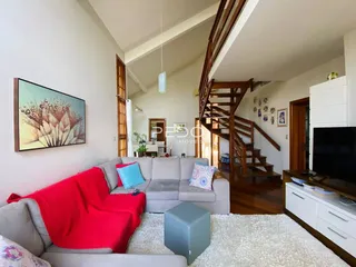 Sala de estar com sofá cinza e tapete claro em um apartamento.