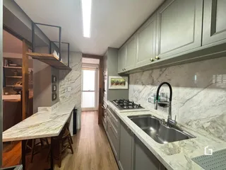 Vista da cozinha com armários e bancadas em mármore claro.
