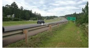 Paisagem externa mostrando uma faixa de terra com vegetação e uma estrutura horizontal.
