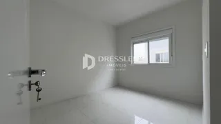 Vista interna de um corredor com paredes brancas e piso claro.