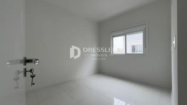 Vista interna de um corredor com paredes brancas e piso claro.