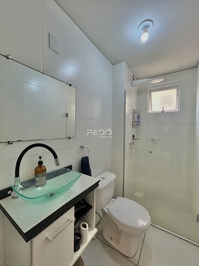 Foto interna de um banheiro moderno com revestimento branco.