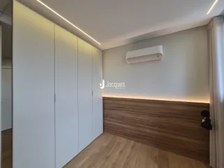Quarto com armários brancos e painel de madeira na parede.