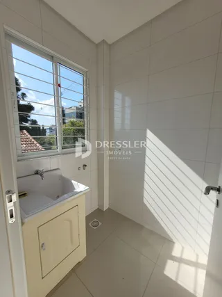 Foto de um banheiro com janela e azulejos claros.
