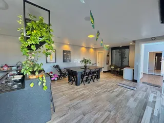 Ambiente amplo com piso de madeira e mesa de jantar em uma residência.