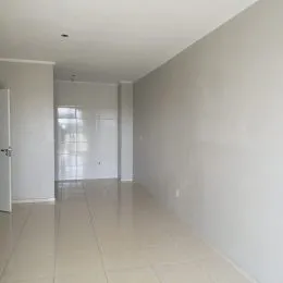 Corredor longo com paredes brancas e piso claro.