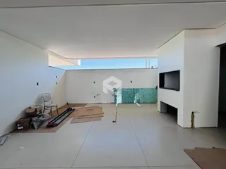 Interior de uma sala em construção com paredes brancas e piso de concreto.