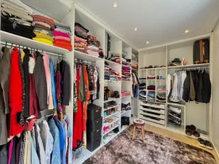 Armários brancos com roupas penduradas e organizadas em um ambiente interno.