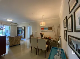 Sala de estar com mesa de jantar de madeira clara.