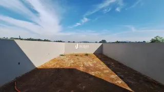 Vista externa de um terreno vazio cercado por uma parede branca.