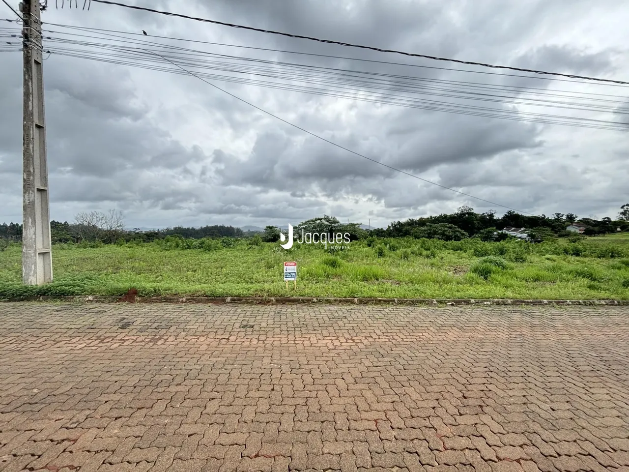 Vista externa de uma propriedade com gramado e área pavimentada.