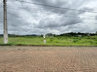 Vista externa de uma propriedade com gramado e área pavimentada.