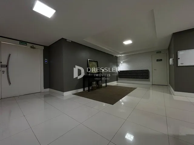 Ambiente interno de uma sala ampla com piso de cerâmica clara.