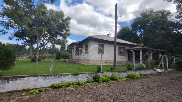 Vista externa de uma casa em Lajeado, Brasil, com um gramado e muro de contenção em primeiro plano.