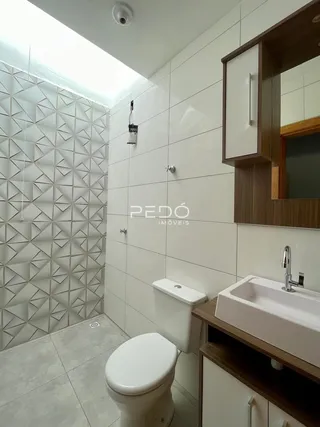 Foto de um banheiro com revestimento de azulejos brancos e louças sanitárias.