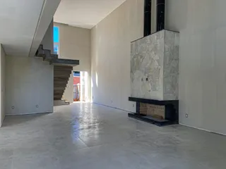 Hall de entrada com piso de concreto polido e lareira de pedra na parede.