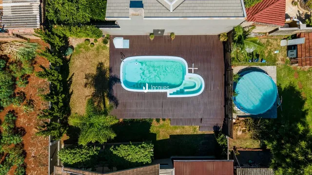 Vista aérea de uma piscina e deck em uma propriedade no Brasil.