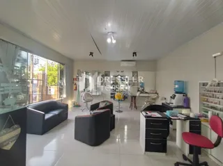 Sala de estar com sofás escuros e grandes janelas.