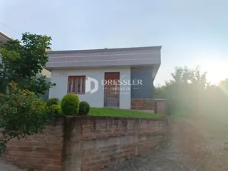 Fachada de uma casa em Lajeado, Brasil, com muro de tijolos e vegetação.