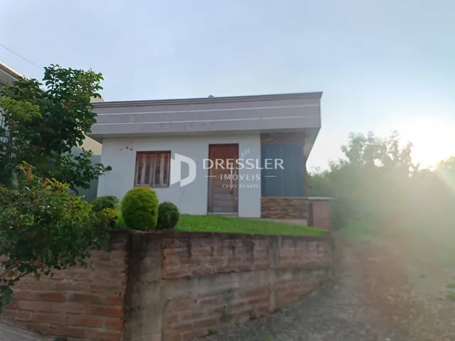 Fachada de uma casa em Lajeado, Brasil, com muro de tijolos e vegetação.