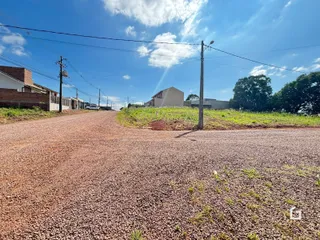 Vista de uma estrada de terra e vegetação em frente a construções no Brasil.
