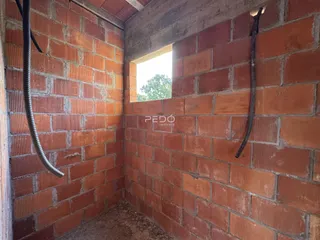 Interior de um cômodo com paredes de tijolo aparente e tubulações.