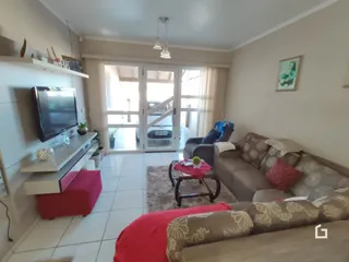 Sala de estar com sofá e televisão em piso cerâmico.