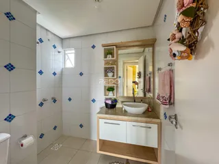 Foto interna de um banheiro com revestimento de azulejos brancos.