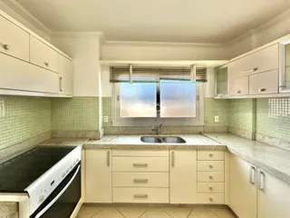 Foto de uma cozinha com armários brancos e revestimento verde.