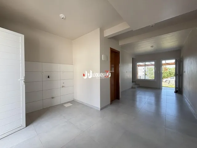 Hall de entrada com paredes brancas e piso claro.