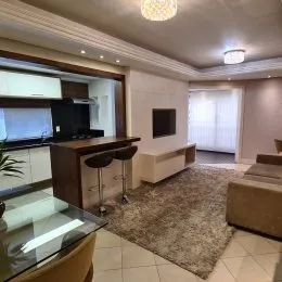 Foto do interior de uma sala com móveis e acabamentos claros.