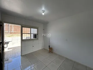 Sala de estar clara com piso de cerâmica e porta de vidro que dá acesso ao exterior.