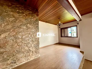 Sala ampla com parede de pedra e teto de madeira.