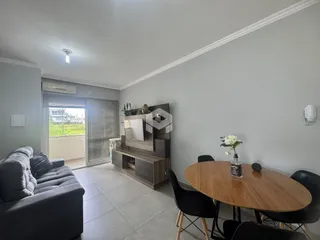 Sala de estar com sofá e mesa de jantar em um apartamento no Brasil.